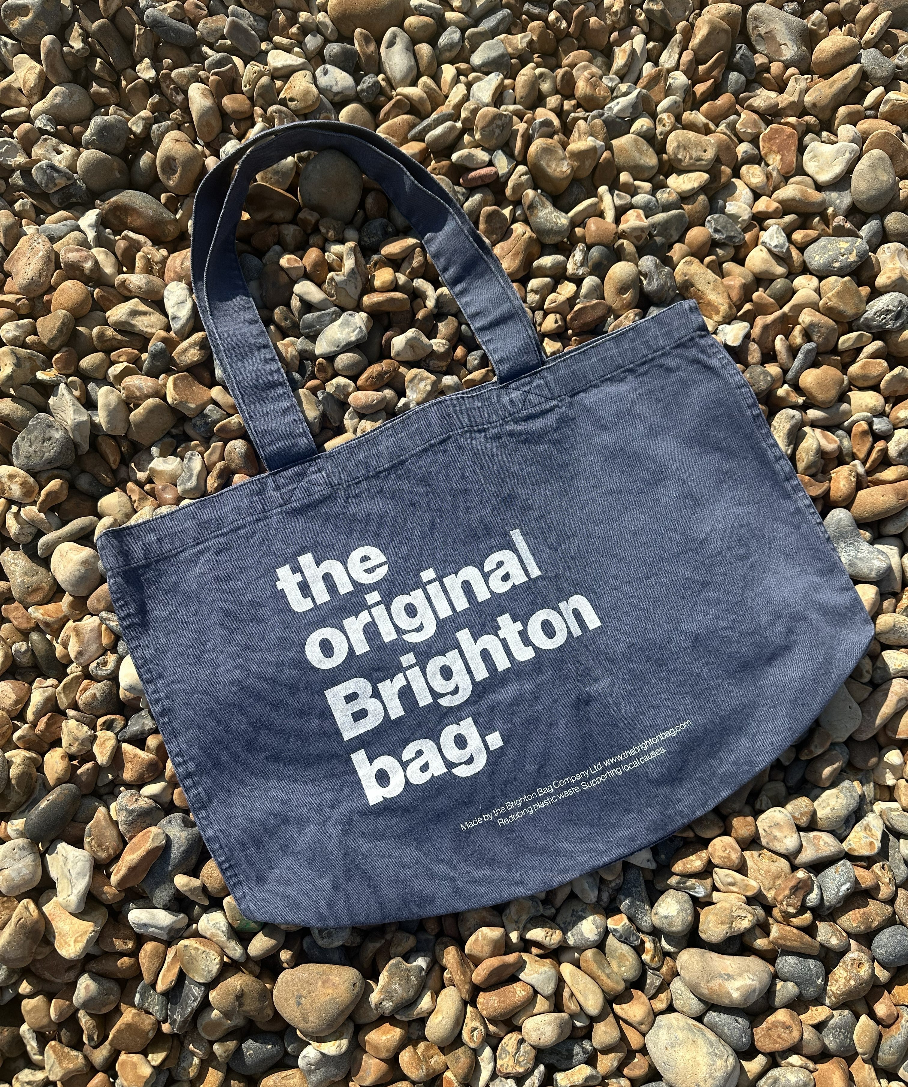 Navy tote bag with 'the original Brighton bag' text on pebbles