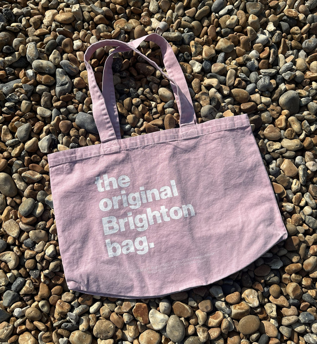 Pink tote bag with 'the original Brighton bag' text on pebbles